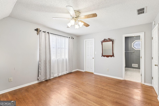 interior space featuring light wood-style floors, baseboards, visible vents, and a textured ceiling