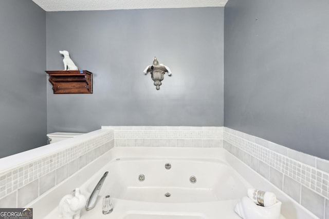 bathroom with a jetted tub, toilet, and a textured ceiling