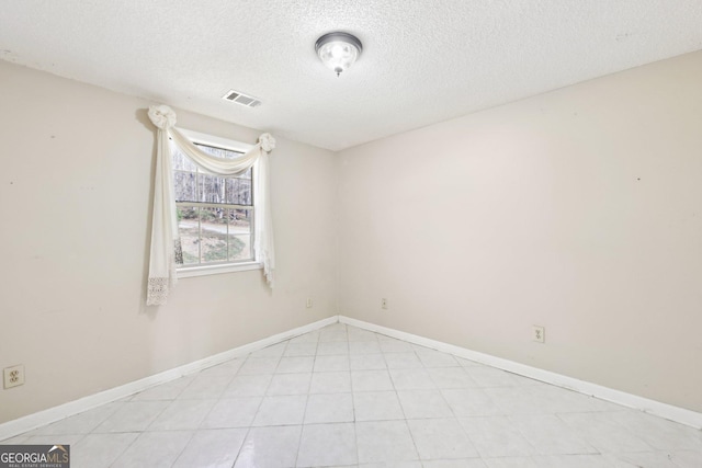 unfurnished room with a textured ceiling, visible vents, and baseboards