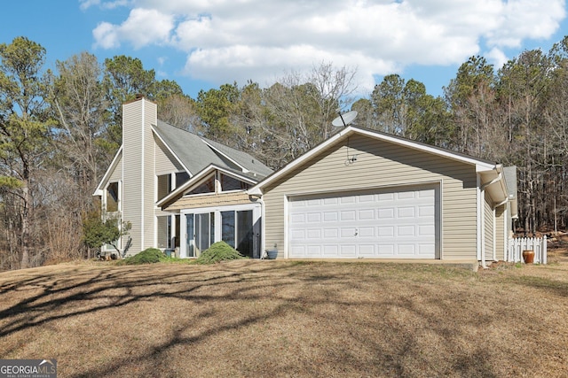 view of front of house featuring a garage, a chimney, a front yard, and a sunroom