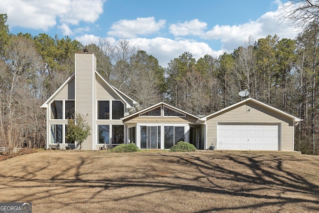 chalet / cabin with an attached garage, driveway, a chimney, and a front lawn