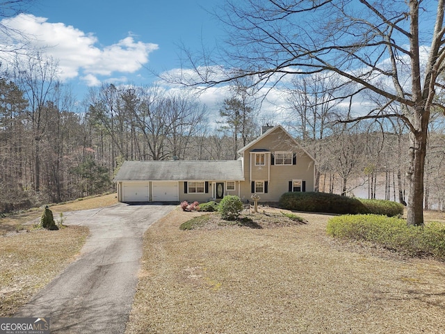 view of front facade with aphalt driveway, a chimney, and a garage