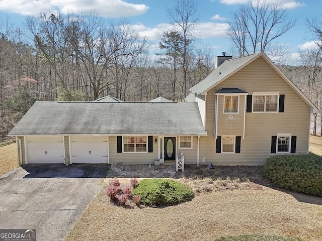 traditional home featuring aphalt driveway, roof with shingles, a chimney, and an attached garage