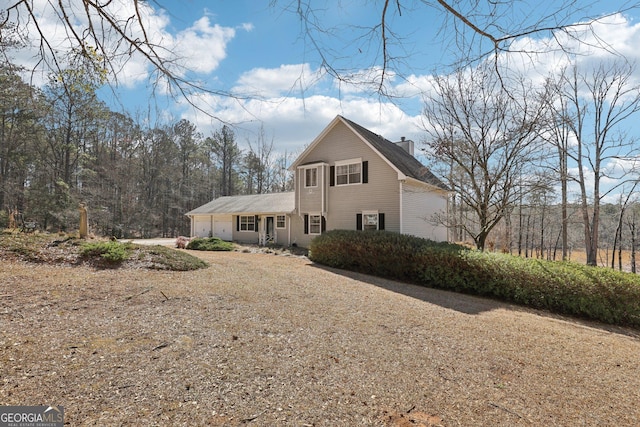 traditional-style home featuring driveway, a chimney, and an attached garage