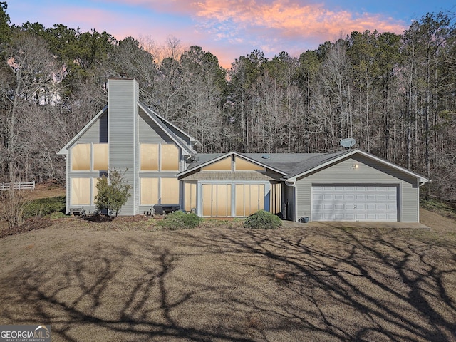 view of front of home with driveway, a front lawn, a chimney, and an attached garage