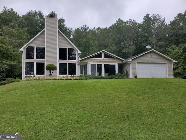 back of property featuring an attached garage, a chimney, and a yard