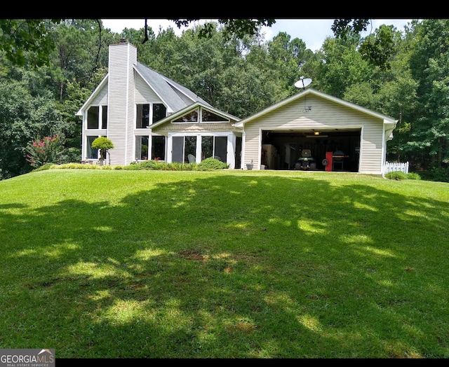 rear view of house with a garage, an outbuilding, a lawn, and a chimney