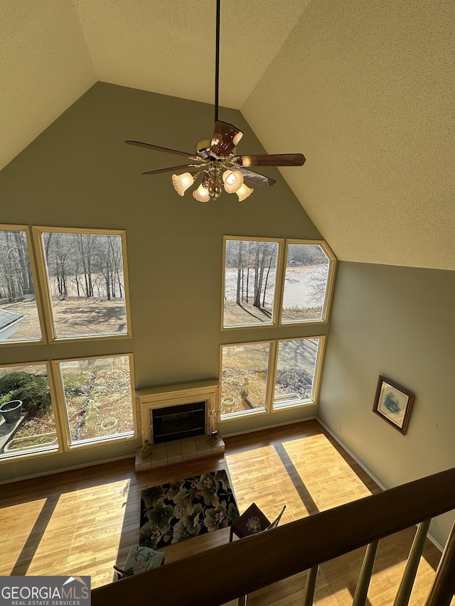 interior space featuring lofted ceiling, a fireplace with raised hearth, a textured ceiling, and wood finished floors