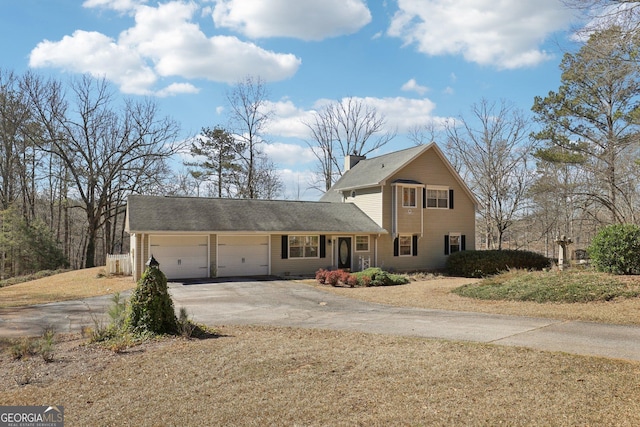 traditional-style house featuring driveway, an attached garage, and a chimney