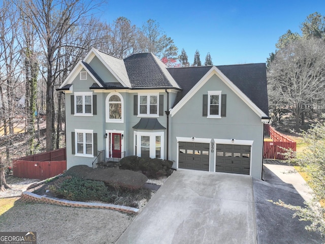 view of front of property featuring concrete driveway, roof with shingles, fence, and stucco siding