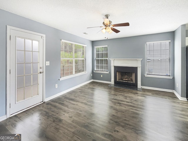 unfurnished living room featuring ceiling fan, dark wood-type flooring, and a textured ceiling