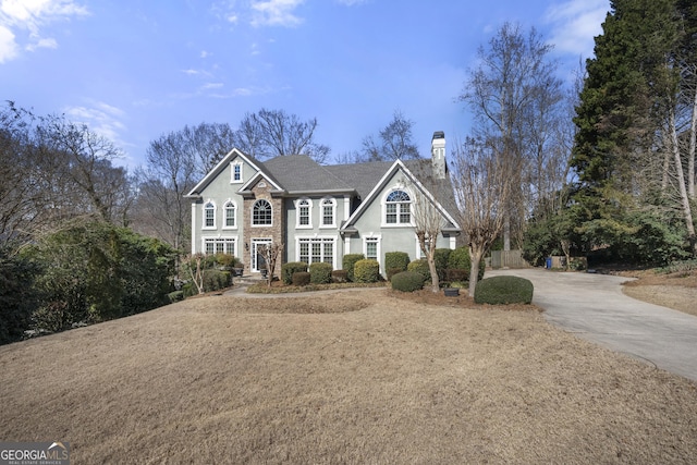 view of front of property featuring a chimney, concrete driveway, and stucco siding