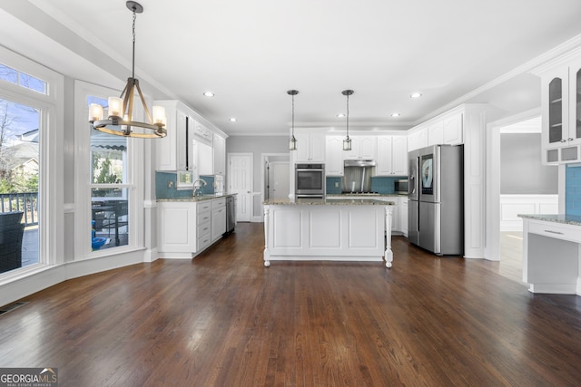 kitchen with glass insert cabinets, light stone counters, decorative light fixtures, stainless steel appliances, and white cabinetry