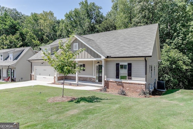 view of front of home with cooling unit, a garage, a front lawn, and a porch