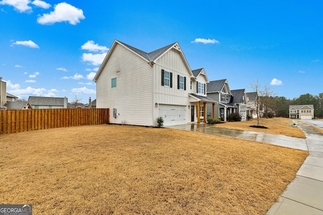 view of home's exterior featuring a garage, driveway, a residential view, fence, and board and batten siding