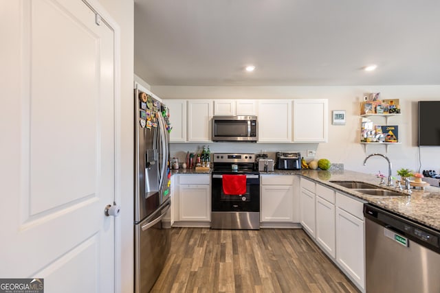 kitchen with stone counters, appliances with stainless steel finishes, sink, white cabinets, and dark hardwood / wood-style flooring