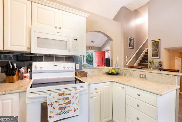 kitchen with white appliances, light stone countertops, white cabinets, and tasteful backsplash