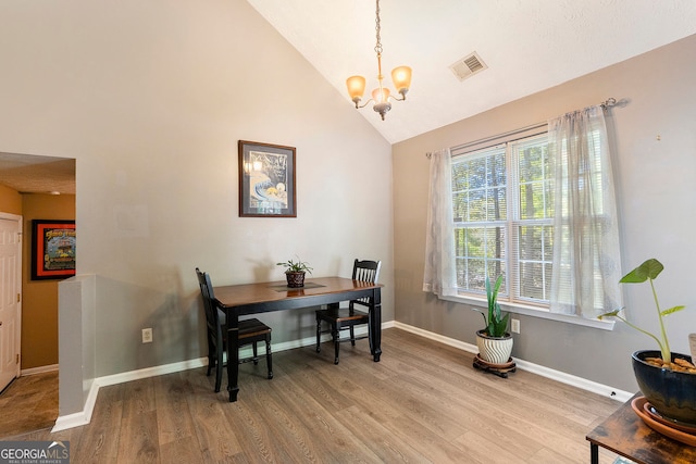 dining space featuring baseboards, visible vents, light wood-type flooring, high vaulted ceiling, and a notable chandelier