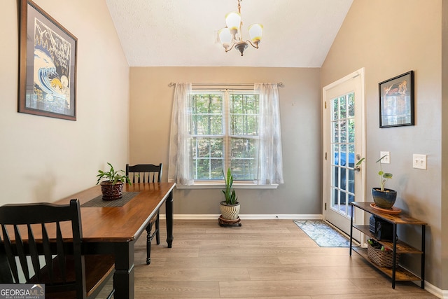 dining area featuring lofted ceiling, light wood finished floors, a chandelier, and baseboards