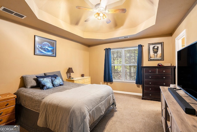 bedroom with light carpet, baseboards, visible vents, and a tray ceiling