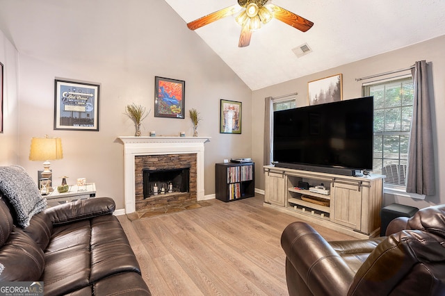 living area with light wood finished floors, visible vents, ceiling fan, a stone fireplace, and baseboards