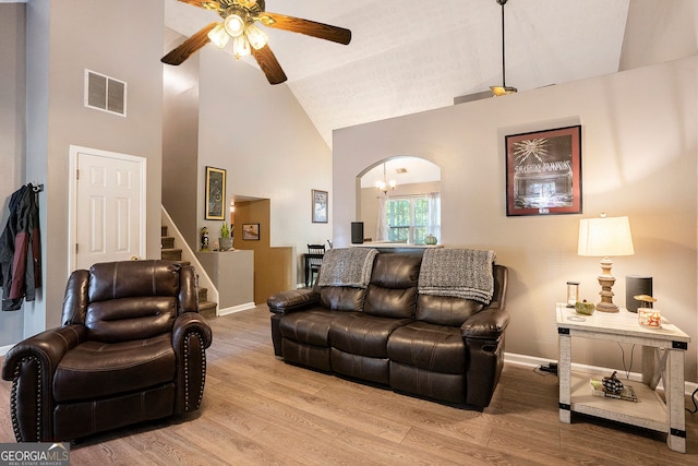 living area featuring light wood-type flooring, high vaulted ceiling, visible vents, and arched walkways