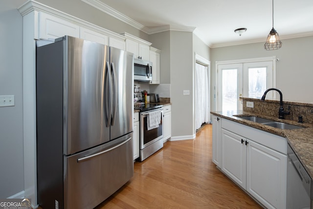 kitchen featuring sink, dark stone countertops, pendant lighting, stainless steel appliances, and white cabinets