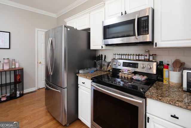 kitchen featuring crown molding, dark stone countertops, stainless steel appliances, tasteful backsplash, and white cabinets