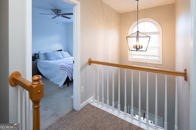 hall featuring carpet and a notable chandelier