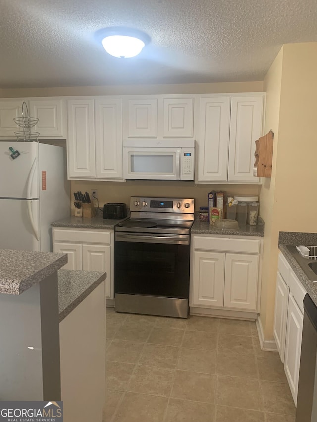 kitchen featuring light tile patterned floors, dark countertops, stainless steel appliances, a textured ceiling, and white cabinetry