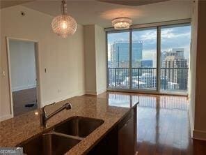 kitchen with a healthy amount of sunlight, sink, light stone counters, and decorative light fixtures