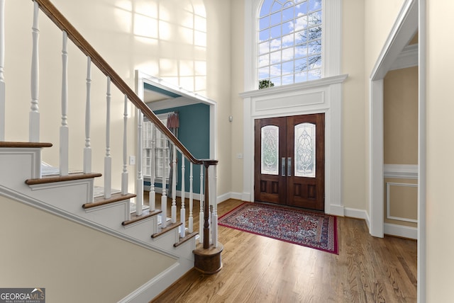 entryway with hardwood / wood-style floors, french doors, and a towering ceiling