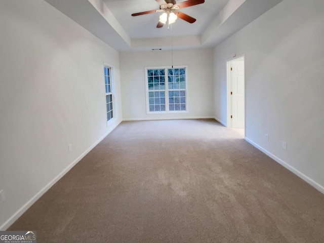 carpeted empty room with ceiling fan and a tray ceiling