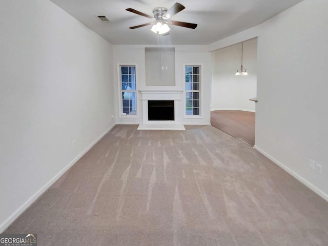 unfurnished living room with ceiling fan with notable chandelier and light colored carpet