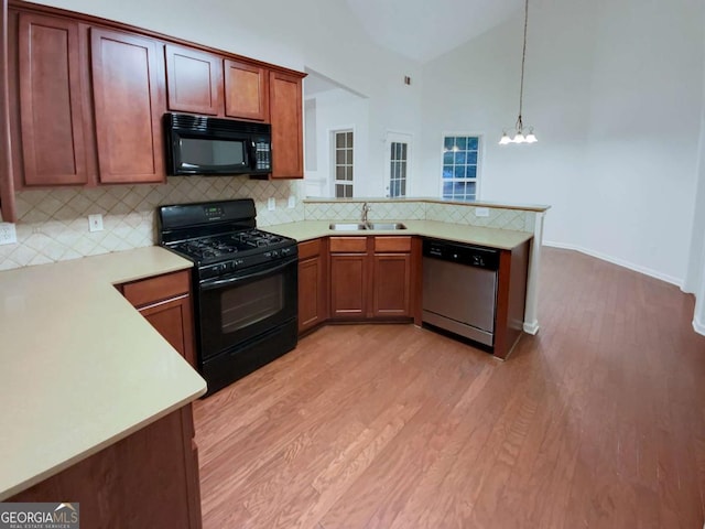 kitchen with sink, decorative light fixtures, kitchen peninsula, and black appliances