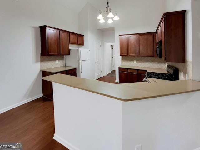 kitchen with pendant lighting, gas range, kitchen peninsula, and white refrigerator