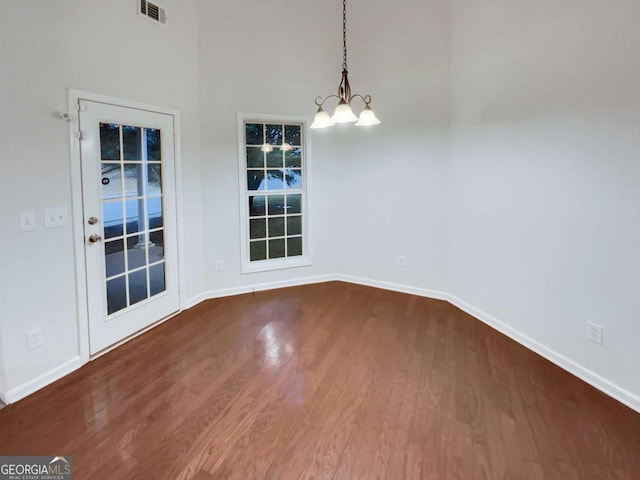 unfurnished dining area with hardwood / wood-style floors and a chandelier