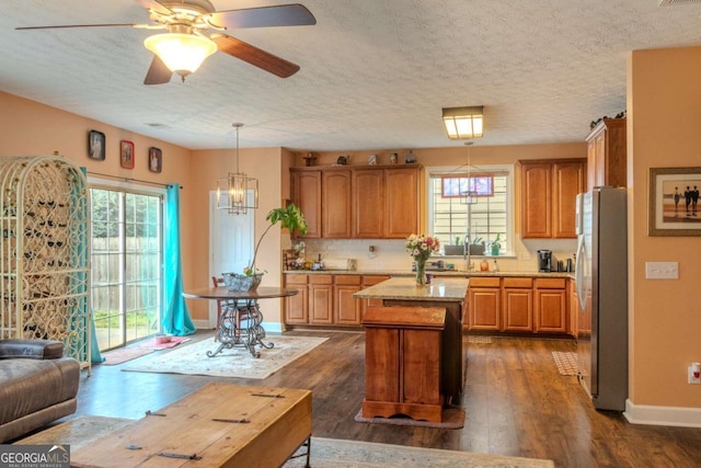 kitchen with dark wood-type flooring, plenty of natural light, a kitchen island, and freestanding refrigerator