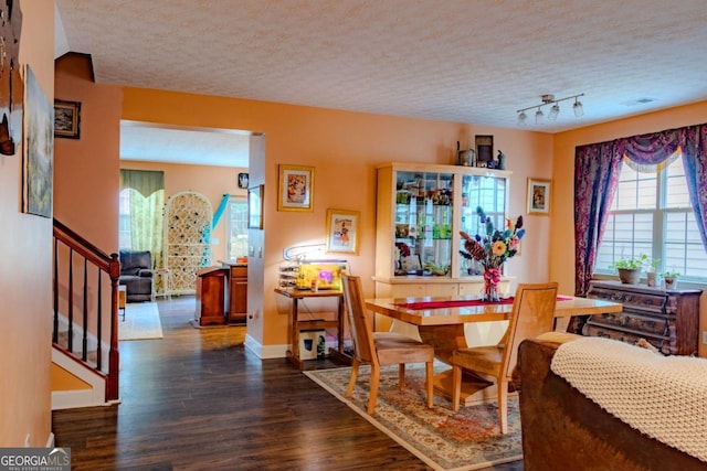 dining room featuring a textured ceiling, dark wood-style flooring, stairway, and baseboards