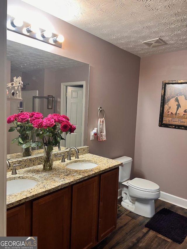 full bath with double vanity, visible vents, a sink, and wood finished floors