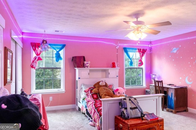 carpeted bedroom with a textured ceiling, ceiling fan, visible vents, and baseboards