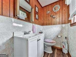 half bathroom with vanity, toilet, and wood finished floors