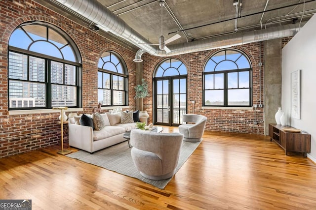 interior space featuring a high ceiling, brick wall, and light wood-type flooring