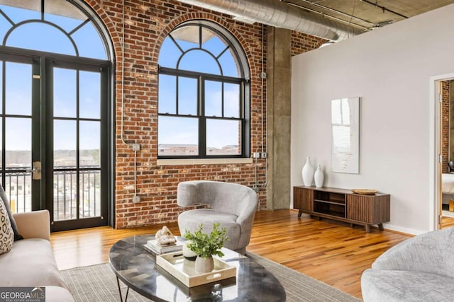 living room featuring a healthy amount of sunlight, brick wall, and light hardwood / wood-style floors