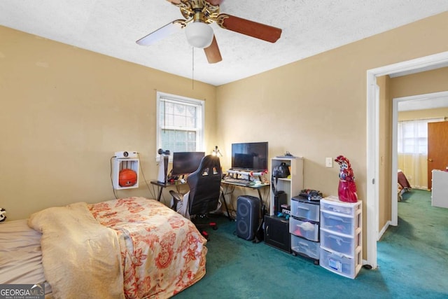 carpeted bedroom featuring ceiling fan and a textured ceiling