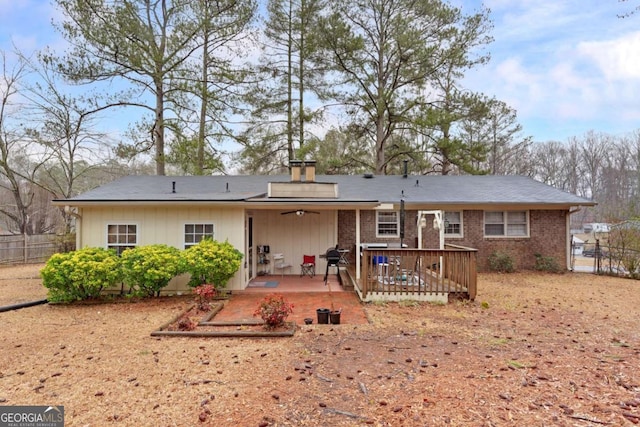 rear view of property featuring a wooden deck, ceiling fan, and a patio area