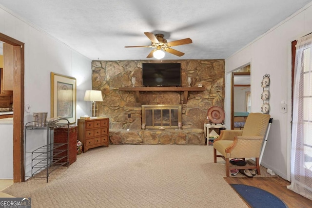 carpeted living room featuring a fireplace, ornamental molding, and ceiling fan