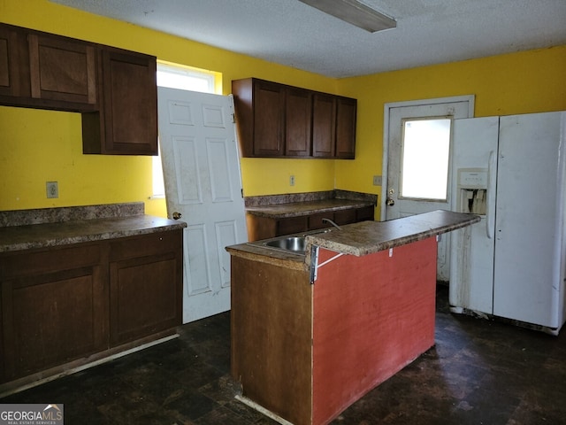 kitchen with a healthy amount of sunlight, white refrigerator with ice dispenser, a center island, and sink