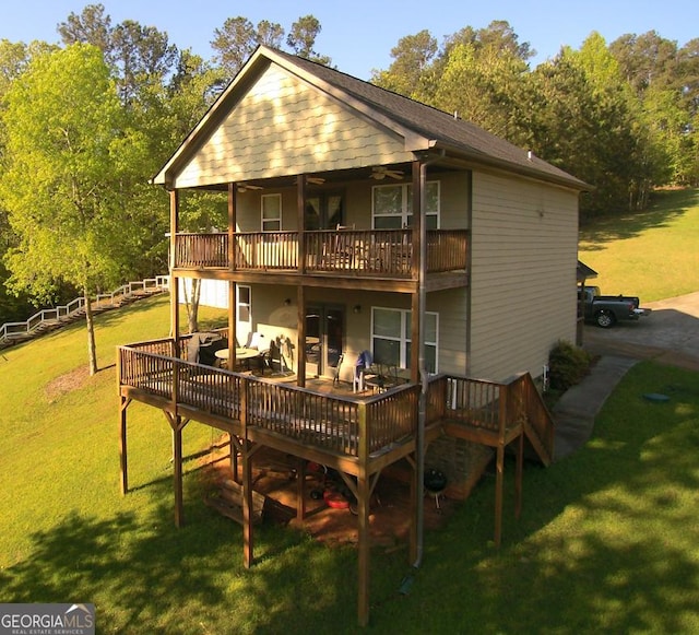 rear view of house featuring a wooden deck and a lawn