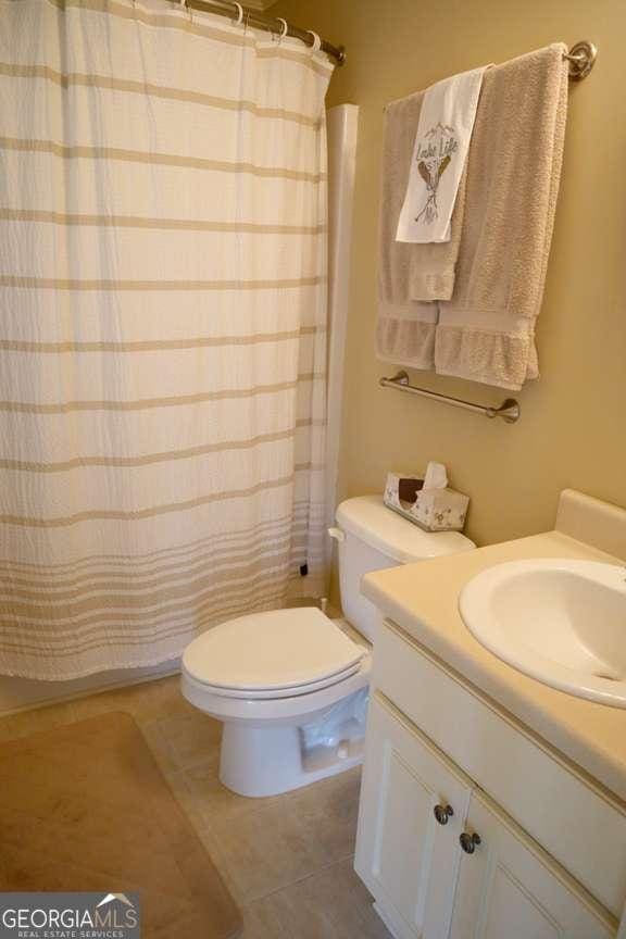 bathroom featuring walk in shower, tile patterned floors, toilet, and vanity